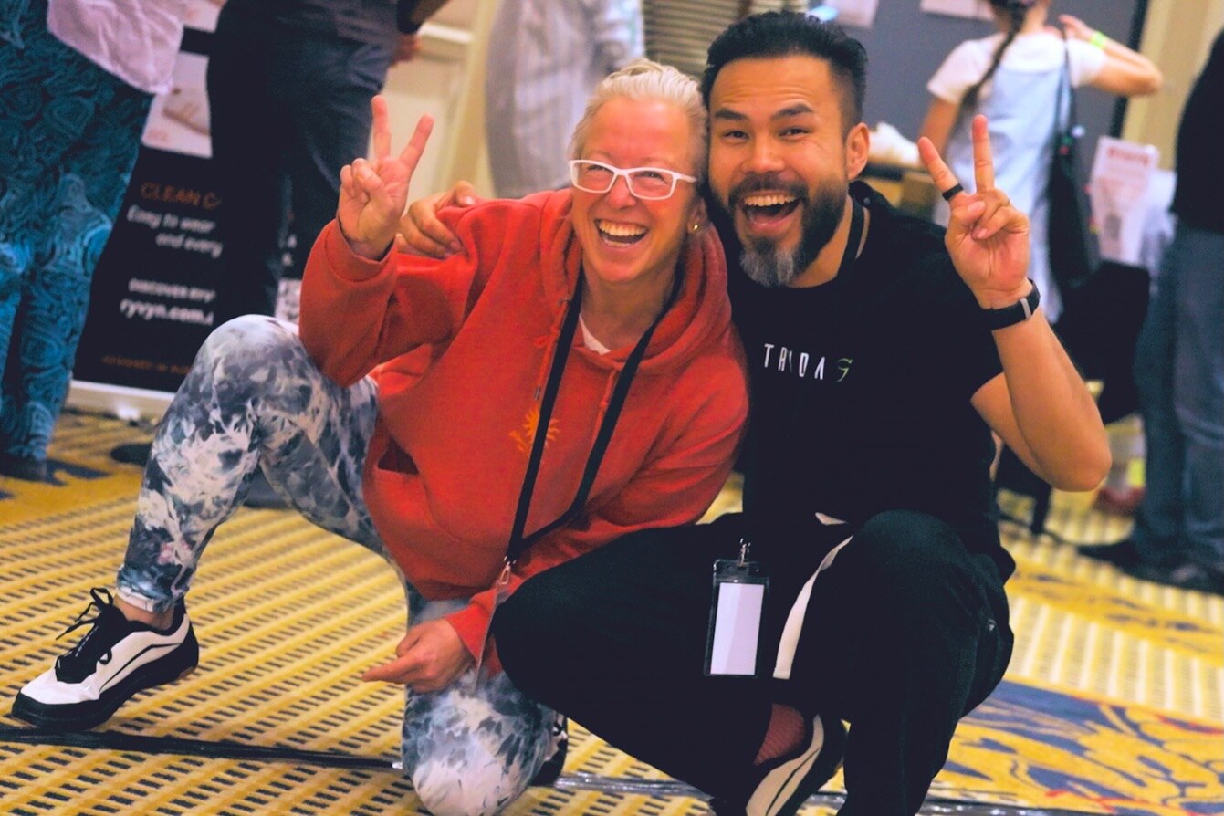 Two attendees smiling together at the expo, photo by The Foot Collective