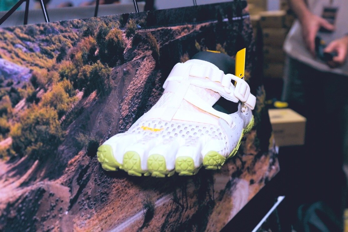 A white toe shoe on display at an exhibitor stand, photo by The Foot Collective